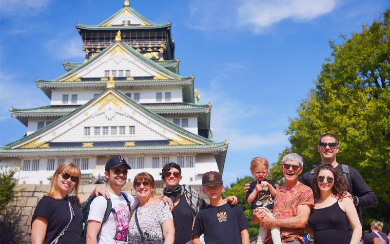Our happy family tour group poses in front of Osaka Castle on a sunny day.