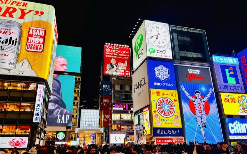 Surrounded by neon lights and lively crowds in Dotonbori, I feel the vibrant heartbeat of Osaka come alive at night.