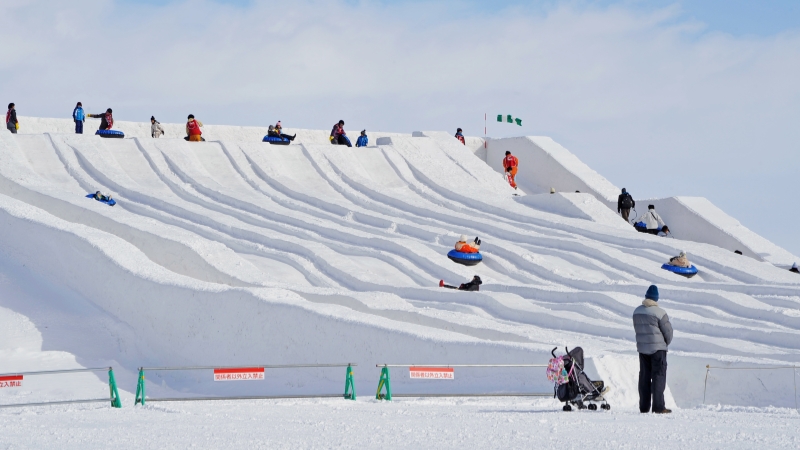 Visitors enjoy giant snow slides at the family-friendly Tsudome site of the Sapporo Snow Festival