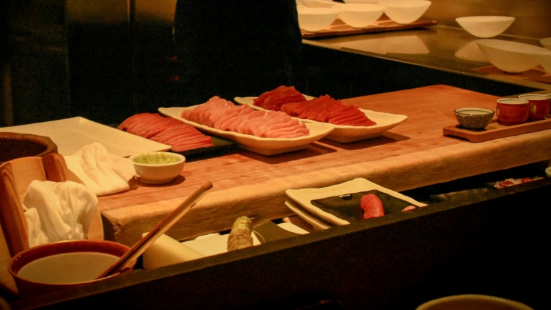 Slabs of pristine, fresh pink and red tuna sit on white platters, ready to be transformed into exquisite sashimi.