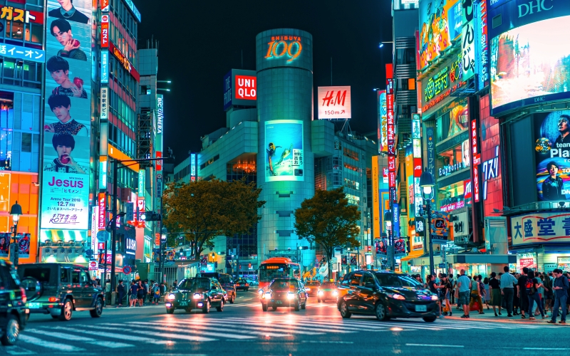 A busy Shibuya street in Tokyo under clear September weather with neon lights and energetic city life at night.