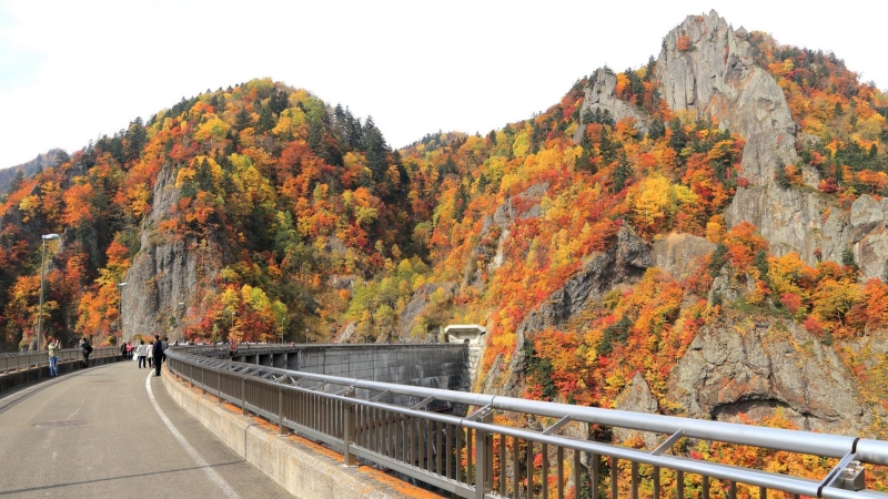 Stunning peak autumn foliage and rocky cliffs at Hoheikyo Dam in Hokkaido.