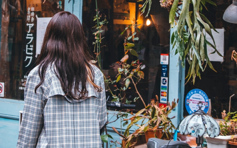 A traveler explores the bohemian alleyways of Nakazakicho, pausing outside a charming retro cafe for a cozy coffee break.