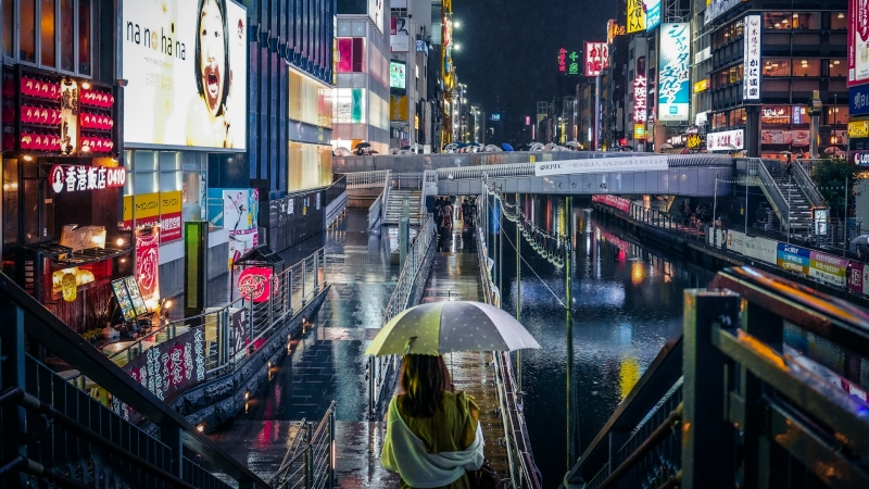 Under a sudden June shower, Dotonbori’s vibrant neon lights shimmer beautifully on the wet pavements, painting Osaka's night in dazzling reflections.